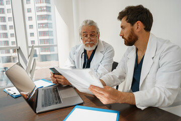 Two doctor colleagues discussing patient diagnosis sitting in office of medicine clinic