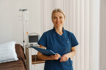 Professional nurse with tablet standing in hospital ward of medicine clinic. High quality photo