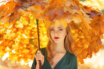 Girl with an umbrella made of maple leaves in the autumn park. Autumn season, art picture