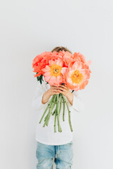 Сheerful boy with a bouquet of beautiful peonies on a white background