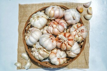 Garlic Cloves and Bulb in vintage rattan bowl isolated on white background.