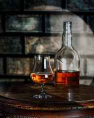 Whiskey, brandy or rum bottle and glass on wooden background