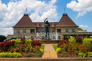 a gorgeous summer landscape with a water fountain with statue of a woman in the center surrounded...