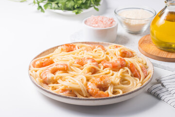 Italian pasta fettuccine or spaghetti in a creamy cheese sauce with shrimp or prawns on a plate