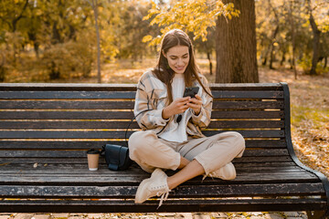 attractive young woman walking in autumn wearing jacket using phone