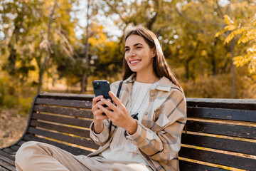 attractive young woman walking in autumn wearing jacket using phone