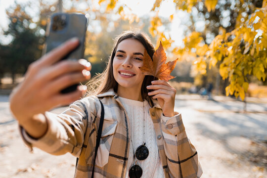 attractive young woman walking in autumn wearing jacket using phone