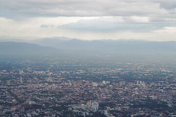 Fototapeta premium Top view of mountain in Chiang Mai City, Thailand. White cloud and dust is above of the mountain while cities can be seen far away.