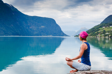 outdoors meditation - relaxed young yoga woman in yoga pose near the lake