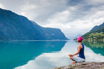 outdoors meditation - relaxed young yoga woman in yoga pose near the lake