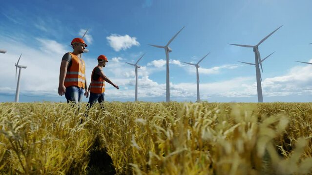 Maintenance workers in a wheat field with wind turbines in the distance, 4K