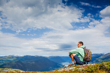 Freedom traveler man sitting upper the fjord and enjoying a beautiful nature