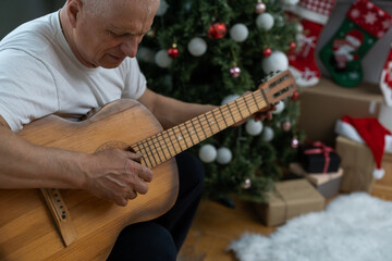 Happy people family concept - Old senior man enjoying the guitar on the sofa in the house at christmas