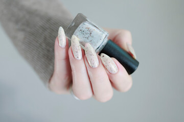beautiful female hands with long nails light white manicure and a bottle of nail polish