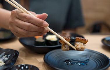 People holding Grilled Eel Sushi rolls in japan restaurant. 