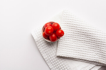top view of cherry tomatoes in bowl on white background with copy space