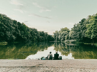 CInematic shot of two men fishing on a lake in the forest