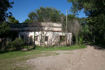 Fototapeta premium gravel road skirting an abandoned house under a very blue sky