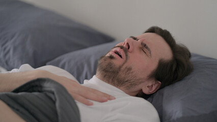 Young Man Coughing while Sleeping in Bed
