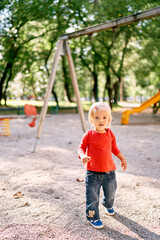 Little girl walks through the playground past the swings. High quality photo
