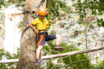 Adorable little girl enjoying her time in climbing adventure park on warm and sunny summer day