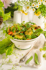 Fresh summer salad with zucchini, carrots and herbs in a bowl on a light wooden table