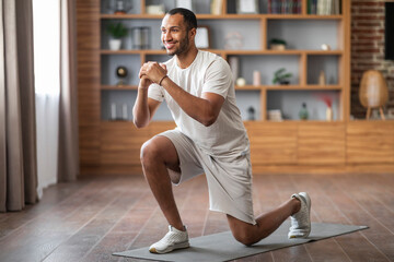 Sporty black man making squat exercise while training at home