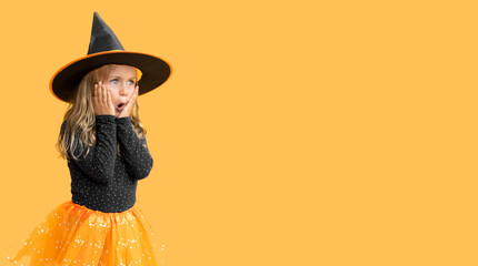 Excited suprise kid girl wearing witch hat costume Halloween isolated yellow studio background....