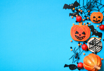 Halloween sweets and decorations on blue background, top view, flat lay, concept of cookie, orange color, copy space.