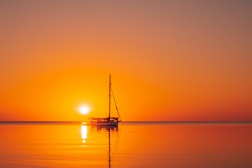 Beautiful view of a sailing boat silhouette in the ocean at sunset in Southern Belize.