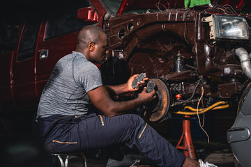 Plakat Male mechanic inspects the steel wheels of a parked car.