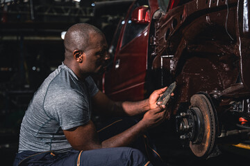 Fototapeta na wymiar Male mechanic inspects the steel wheels of a parked car.