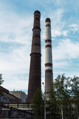 Old plant pipes on blue sky background. Industrial heat-energy center with tall chimney tubes