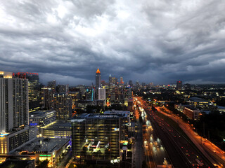 Fototapeta premium Midtown Atlanta Georgia, Night lights and storm clouds with highway traffic. Drone shot.