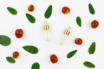 Chinese date fruit and oil. Jojoba oil in a transparent bottle with a dropper and fresh jojoba fruit on a white background