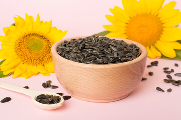 Sunflower seeds and flowers on color background