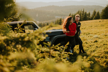 Fototapeta na wymiar Smiling couple preparing hiking adventure with backpacks by terrain vehicle