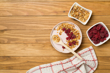 Bowl with granola, yogurt and fresh berries on wooden background, top view