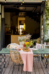 Beautifully decorated dining table with flowers on wooden terrace of country house
