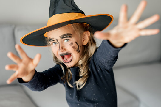 funny little girl wearing witch hat costume and make up. Happy child in halloween costume ready for Halloween party