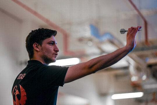 Darts player from low angle aiming the target