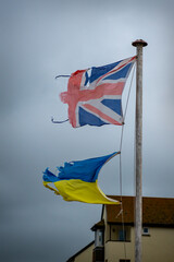Ripped and tatty Union jack flag and Ukrainian flag fly together. Shredded and worn out they fly...