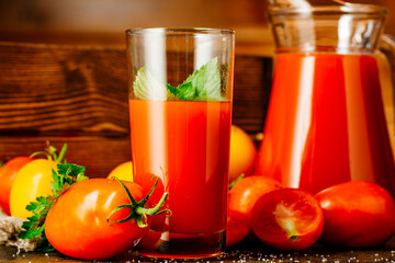Fresh tomato juice in a glass with tomatoes. Vegetable tomato drink for healthy eating on a wooden background.