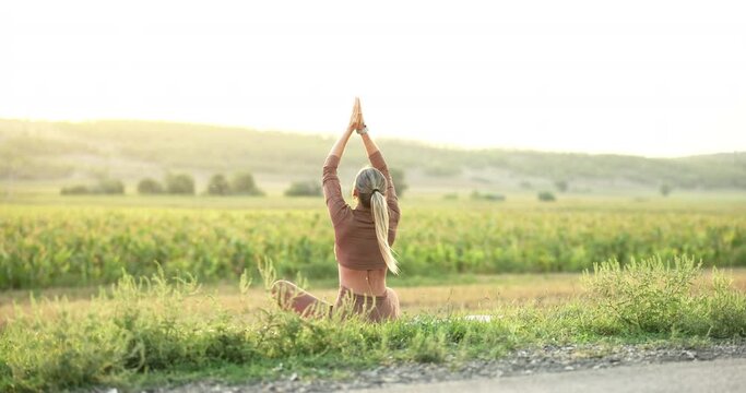 Silhouette of young woman practicing yoga on the nature at sunset. Active meditation a relax concept. Woman meditation in nature in the park. Sport recreation concept sunset.