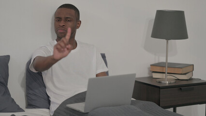Rejecting African Man with Laptop Shaking Head as No Sign in Bed