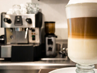 Close up of a glass cup with hot cappuccino prepared in the coffee machine