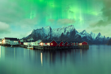Northern lights above mountainous village near lake