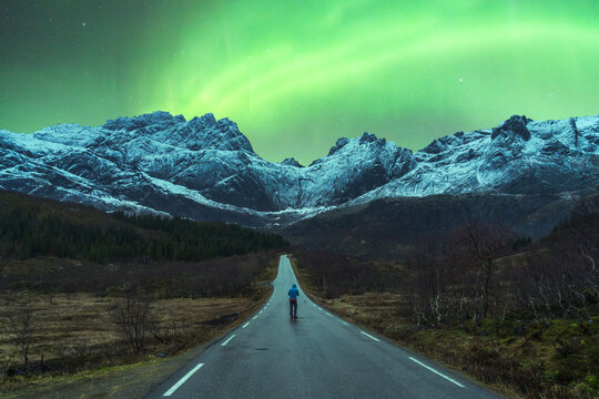 Traveler standing on road under sky with aurora