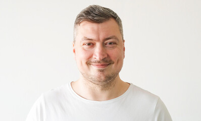 Handsome man. Positive mood. Good nature. Confident smiling guy in white t-shirt on light background.