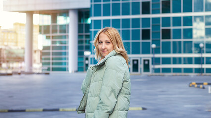 A fashion portrait of a beautiful blonde posing the city on a blue background. An attractive beautiful girl. Model. Women's fashion. Modern background. An attractive elegant woman. Blue background